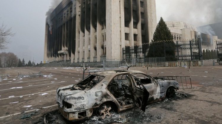 Carro queimado em frente a um prédio do governo incendiado durante protestos em Almaty