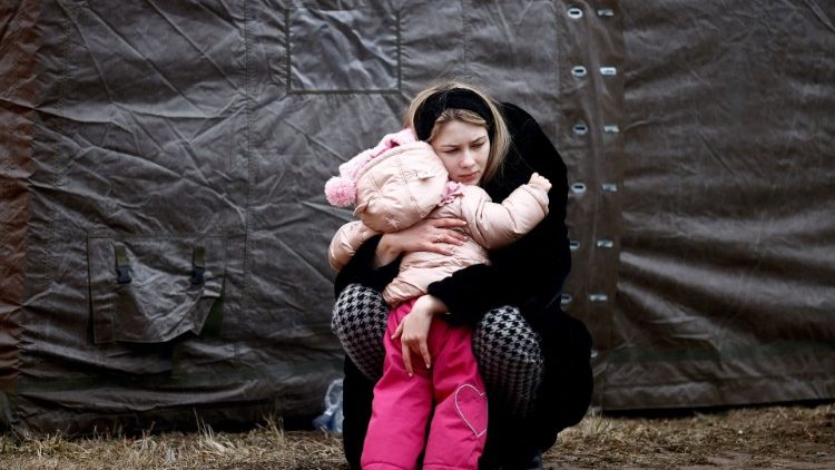 A woman fleeing the Russian invasion of Ukraine embraces a child in a refugee camp in Przemysl, Poland