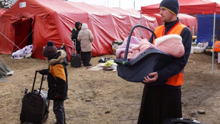 Ein Priester hält in der Slowakei ein Flüchtlingskind aus der Ukraine im Arm 