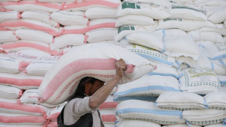 A worker carries a sack of wheat flour outside a food shop in Sanaa, Yemen