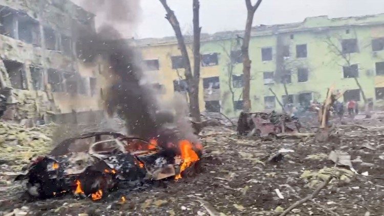 Auto hořící před zničenou dětskou nemocnicí, Mariupol, 9. března 2022
