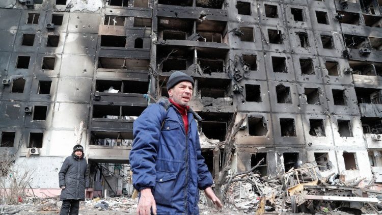 Pessoas se reúnem perto de um bloco de apartamentos, que foi destruído durante o conflito Ucrânia-Rússia na cidade portuária sitiada de Mariupol, Ucrânia, em 17 de março de 2022 REUTERS/Alexander Ermochenko