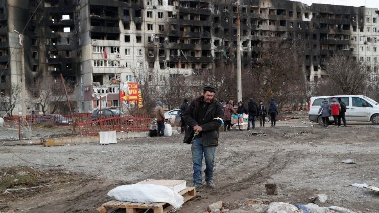 Pessoas se reúnem perto de um bloco de apartamentos, que foi destruído durante o conflito Ucrânia-Rússia na cidade portuária sitiada de Mariupol, Ucrânia, em 17 de março de 2022 REUTERS/Alexander Ermochenko