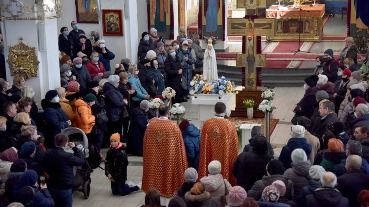 Pessoas rezam pela paz na Ucrânia em frente à réplica da estátua original de Nossa Senhora de Fátima, na Igreja da Natividade da Santíssima Virgem, em meio à invasão russa da Ucrânia, em Lviv, Ucrânia. (REUTERS/ Pavlo Palamarchuk)