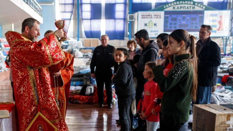 Um bispo greco-católico realiza um culto para pessoas que fugiram da invasão russa da Ucrânia, em uma acomodação temporária dentro de um complexo esportivo em Uzhhorod, Ucrânia, 20 de março de 2022. REUTERS/Serhii Hudak