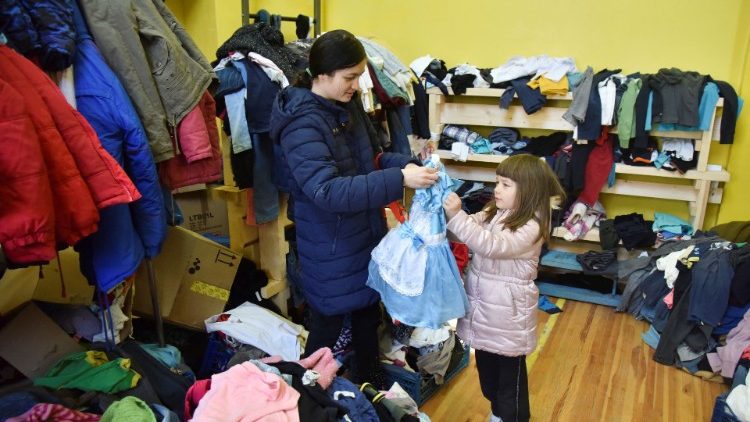 Uma mulher e uma criança escolhem roupas em uma sede de ajuda humanitária, em meio à invasão russa da Ucrânia, em Lviv, Ucrânia, 22 de março de 2022. REUTERS/Pavlo Palamarchuk