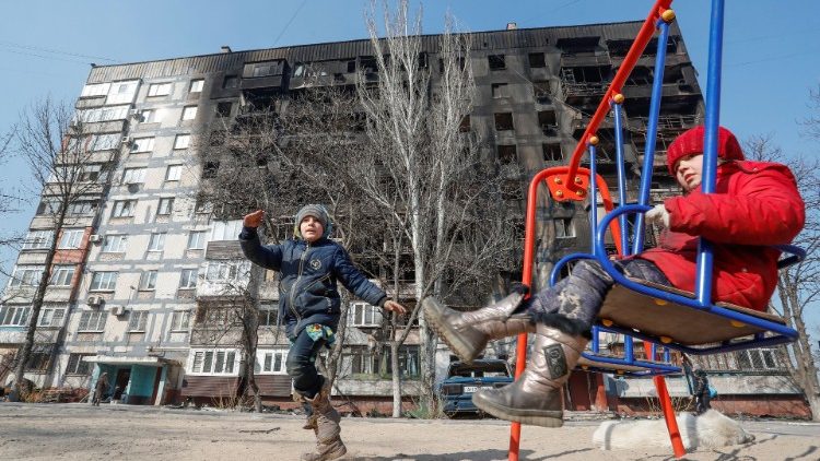 Crianças brincam em frente a um prédio danificado em combates durante o conflito Ucrânia-Rússia, no porto sul sitiado de Mariupol, Ucrânia 23 de março de 2022 REUTERS/Alexander Ermochenko
