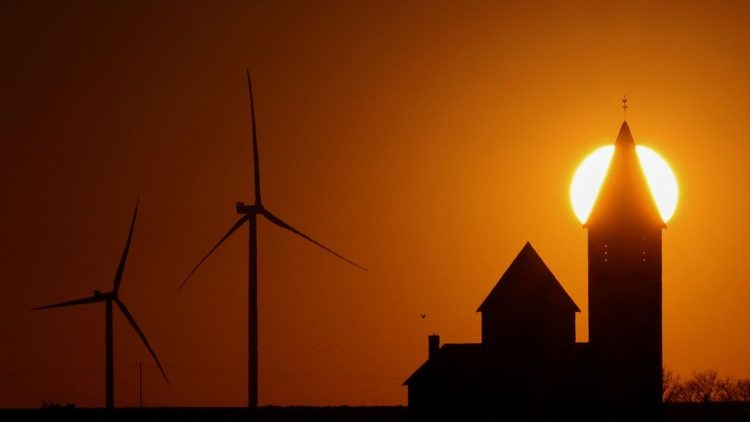 Power-generating windmill turbines and the church of Noreuil village are pictured during sunset at a wind park near Cambrai