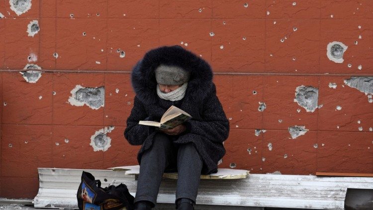 Uma moradora local lê um livro perto de um prédio danificado durante o conflito Ucrânia-Rússia na cidade portuária de Mariupol, no sul da Ucrânia, em 3 de abril de 2022 REUTERS/Stringer