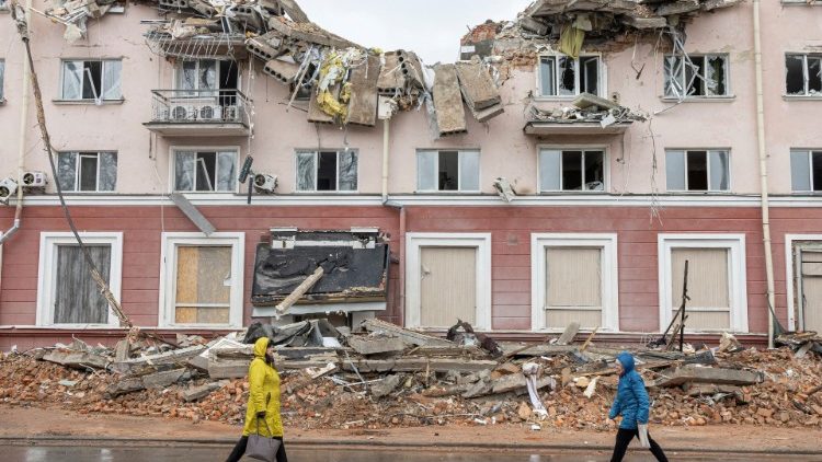 Mulheres caminham ao longo de uma rua em frente ao destruído Hotel Ucrânia, enquanto a invasão russa da Ucrânia continua, em Chernihiv, Ucrânia, 6 de abril de 2022. REUTERS/Marko Djurica