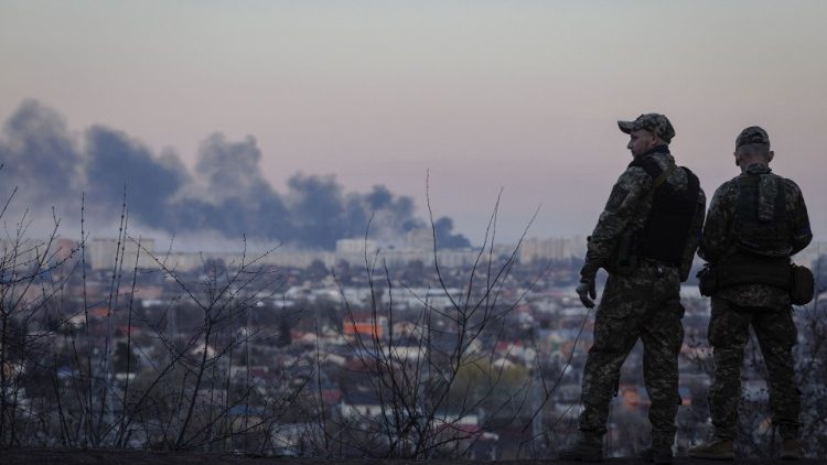 Ukrainische Soldaten betrachten eine Rauchsäule, die in Charkiw aufsteigt