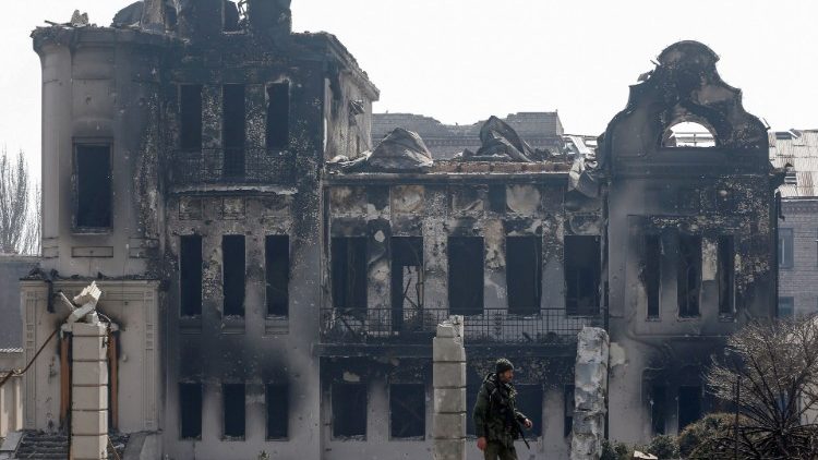 Membros do serviço de tropas pró-Rússia ficam perto de um prédio queimado durante o conflito Ucrânia-Rússia na cidade portuária de Mariupol, no sul da Ucrânia, em 10 de abril de 2022 REUTERS/Alexander Ermochenko