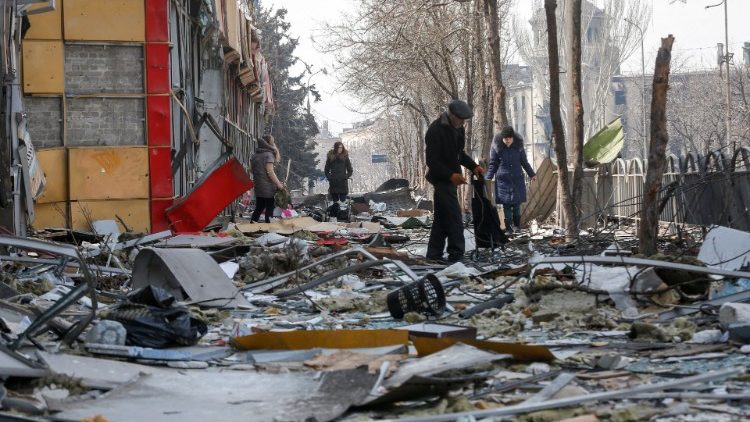Moradores caminham por uma rua perto de um prédio destruído durante o conflito Ucrânia-Rússia, na cidade portuária de Mariupol, no sul da Ucrânia, em 10 de abril de 2022. REUTERS/Alexander Ermochenko