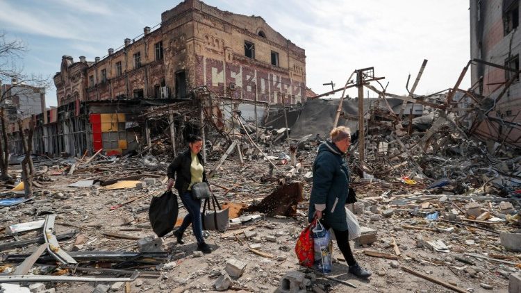 Moradores carregam seus pertences perto de prédios destruídos durante o conflito Ucrânia-Rússia, na cidade portuária de Mariupol, no sul da Ucrânia, em 10 de abril de 2022. REUTERS/Alexander Ermochenko