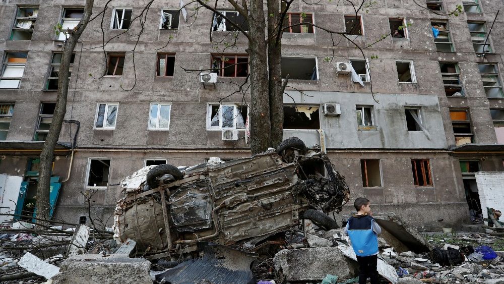 Menino prximo a veculo e prdio atingido por mssil em Mariupol. (REUTERS/Alexander Ermochenko)