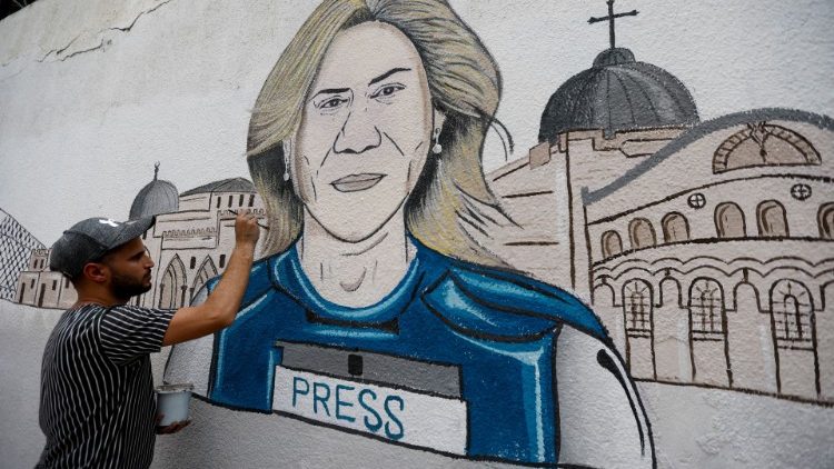 In the Gaza Strip, a man works on a mural depicting slain Al Jazeera reporter Shireen Abu Akleh
