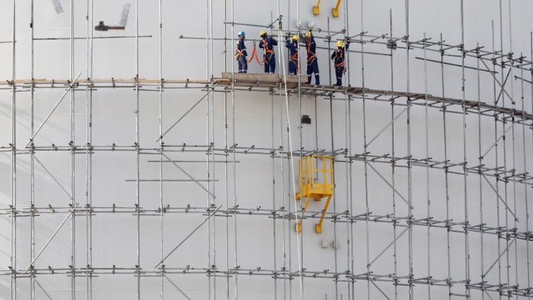 Construction workers stand on a scaffolding on an oil tank, Lagos, Nigeria