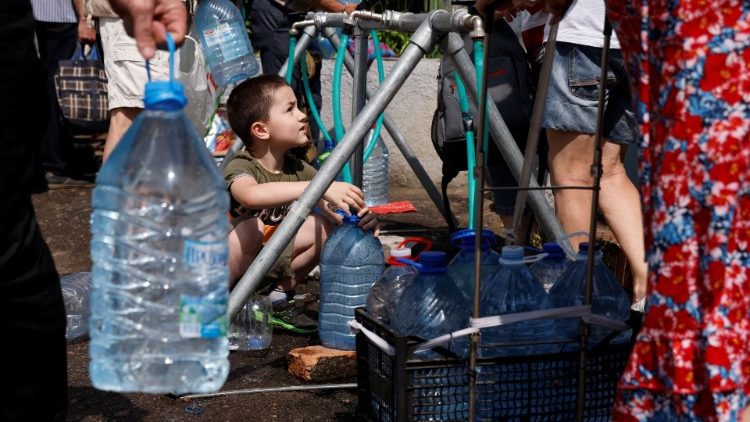 Olexander Bulba, 7, coleta água para seu pai Grigorii em um ponto de distribuição da Cruz Vermelha, enquanto os ataques da Rússia à Ucrânia continuam, em Mykolaiv, Ucrânia 10 de junho de 2022. REUTERS/Edgar Su
