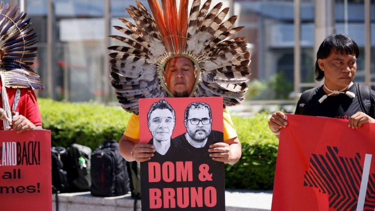 Un indigeno tiene un cartello con i ritratti del giornalista britannico Dom Phillips e del brasiliano Bruno Pereira mentre partecipa a una protesta a Bruxelles