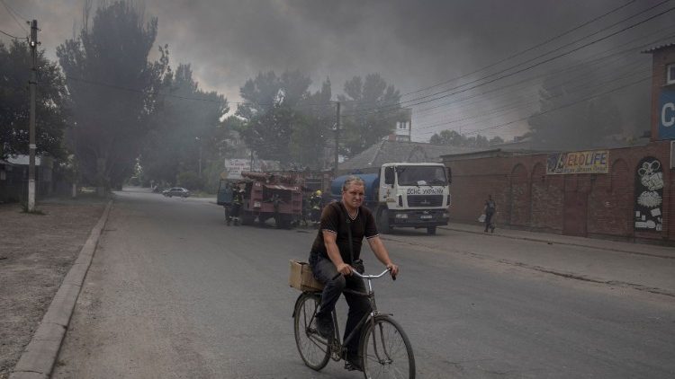 Ucraniano de bicileta em meio à fumaça após ataque russo em Sloviansk. (REUTERS/Marko Djurica