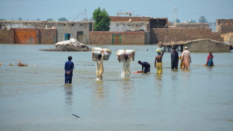 Des victimes d'inondations pataugent dans les eaux de crue après les pluies et les inondations de la mousson à Dera Allah Yar, Jafferabad au Pakistan, le 31 août 2022.