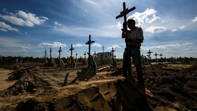 Wolontariusz umieszczający krzyż na grobie jednej z niezidentyfikowanych ofiar rosyjskich zbrodni w Buczy