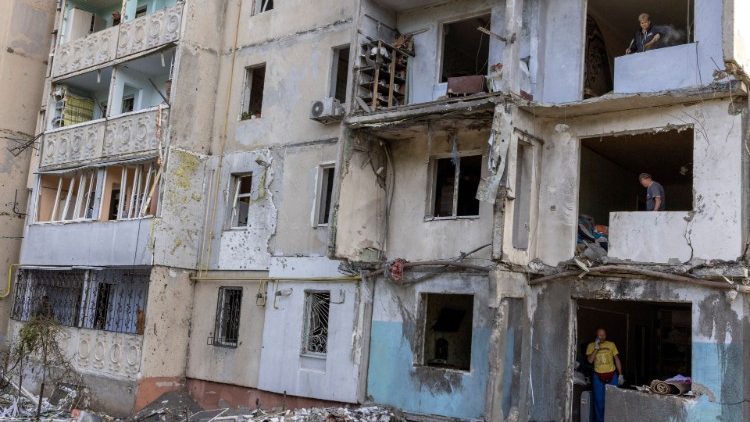 Pessoas ficam de pé, inspecionam e limpam seus apartamentos em um prédio residencial destruído por uma greve, em meio à invasão russa da Ucrânia, em Mykolaiv, Ucrânia, 14 de setembro de 2022. REUTERS/Umit Bektas