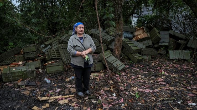 A moradora local Olena Kushnir fica em frente a caixas de munição perto de sua casa destruída, em meio ao ataque da Rússia à Ucrânia, na vila de Nova Husarivka, recentemente libertada pelas Forças Armadas Ucranianas, na região de Kharkiv, Ucrânia 15 de setembro de 2022. REUTERS/Gleb Garanich