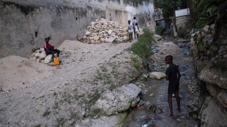 Children collect fresh water at a stream in Port-au-Prince