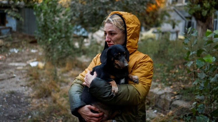 Uma mulher carrega um cachorro em um local de um edifício residencial fortemente danificado por um ataque de mísseis russos, em meio ao ataque ao país, em Mykolaiv, Ucrânia, em 18 de outubro de 2022. REUTERS/Valentyn Ogirenko