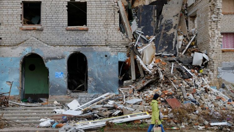 Uma mulher passa por um prédio danificado durante o conflito Rússia-Ucrânia