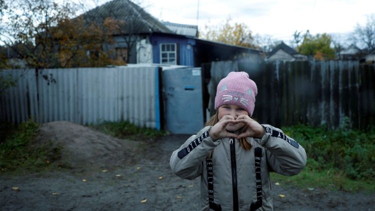 Criança ucraniana faz um coração com as mãos antes de receber pacote com ajudas em Drobysheve, região do Donbass. (REUTERS/Clodagh Kilcoyne)