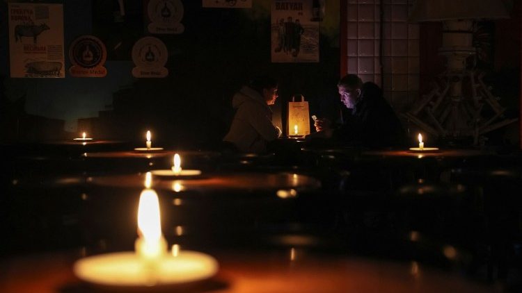 Menschen sitzen in einer mit Kerzen beleuchteten Kneipe während eines Stromausfalls, nachdem wichtige zivile Infrastrukturen durch russische Raketenangriffe in Lviv getroffen wurden