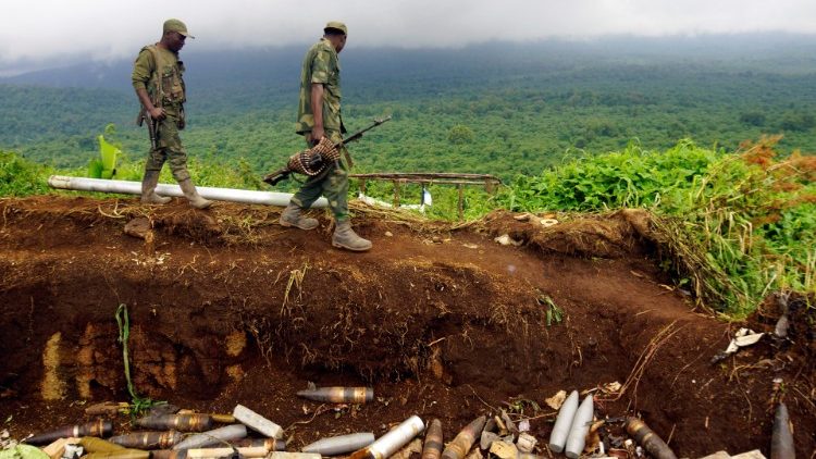 कांगो के सैन्यकर्मी एम23 विद्रोहियों द्वारा इस्तेमाल की जाने वाली एक शस्त्रागार साइट के पास से गुज़रते हुए