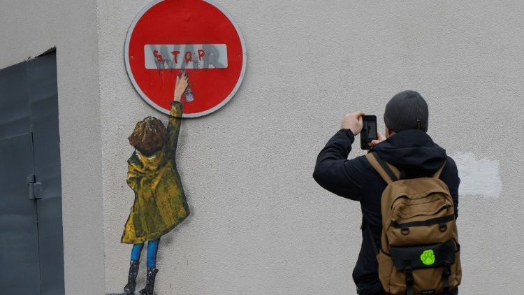 Um homem tira uma foto de uma obra de arte do famoso artista de rua Tvboy no centro da cidade, em meio ao ataque da Rússia à Ucrânia, em Bucha, nos arredores de Kyiv, Ucrânia, 29 de janeiro de 2023. REUTERS/Valentyn Ogirenko