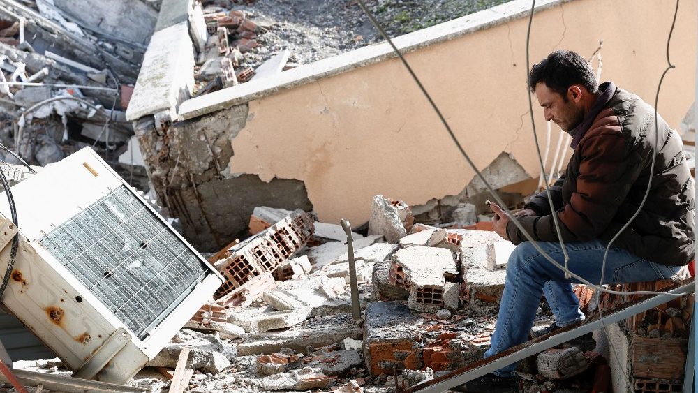Uma pessoa senta-se no local da unidade de terapia intensiva do hospital estadual desmoronado de Iskenderun aps um terremoto em Iskenderun, distrito de Hatay, Turquia, 7 de fevereiro de 2023. REUTERS/Benoit Tessier