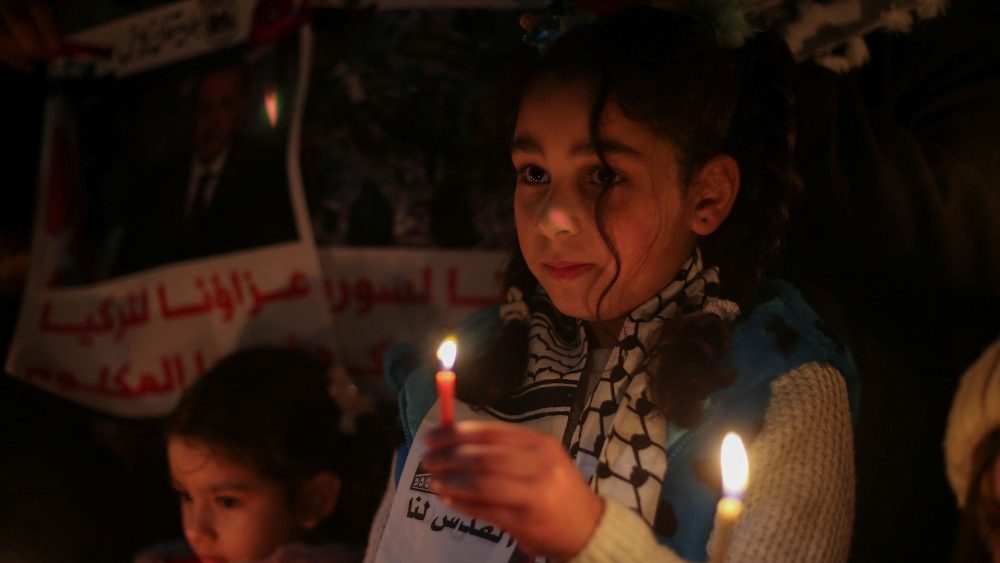 Uma crian?a palestina segura uma vela para expressar solidariedade s vtimas de um terremoto na Turquia e na , em Khan Younis, no sul da Faixa de Gaza, 7 de fevereiro de 2023. REUTERS/Ibraheem Abu Mustafa