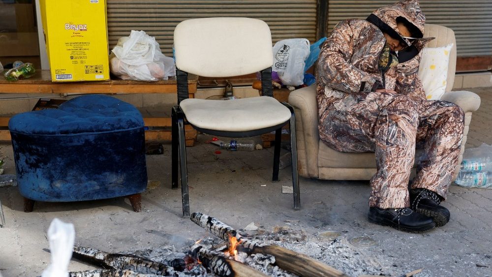 Uma pessoa descansa enquanto se aquece ao lado de um incndio, aps um terremoto mortal, em Kirikhan, Turquia, 8 de fevereiro de 2023 REUTERS/Piroschka van de Wouw