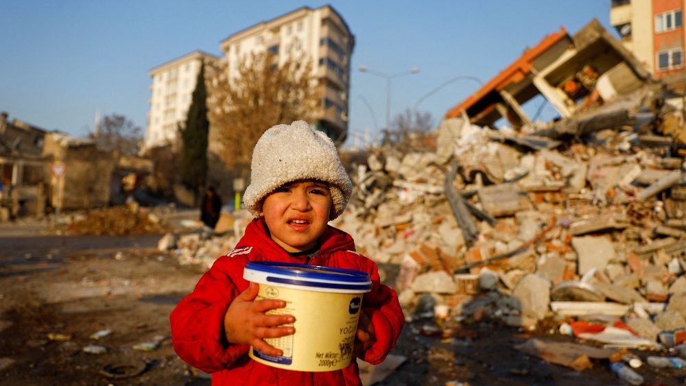 Uma crian?a segurando um recipiente de plstico olha em meio aos escombros, aps um terremoto mortal em Kahramanmaras, Turquia, 14 de fevereiro de 2023. REUTERS/Suhaib Salem