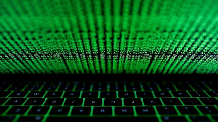 La tastiera di un computer illuminata da un codice informatico 