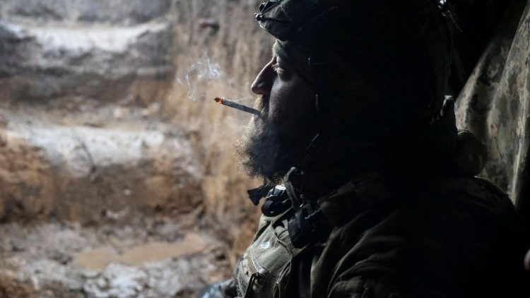 A Ukrainian service member smokes in a shelter at a front line near the city of Bakhmut