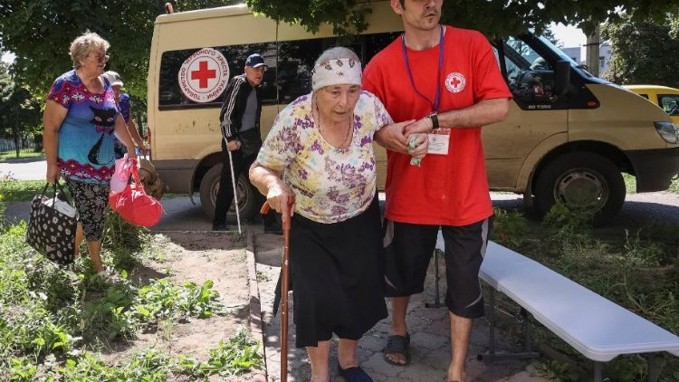 Um voluntário da Cruz Vermelha ajuda uma idosa a evacuar da cidade de Kupiansk-Vuzlovyi na região de Kharkiv, em meio ao ataque da Rússia à Ucrânia, em Kharkiv, Ucrânia, 15 de agosto de 2023. REUTERS/Vyacheslav Madiyevskyy