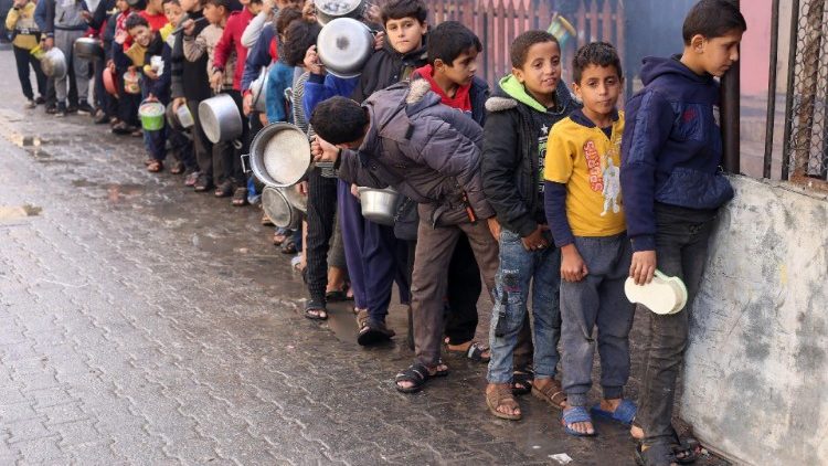Palestinian children carry pots as they queue to receive food cooked by a charity kitchen, in Rafah in the southern Gaza Strip