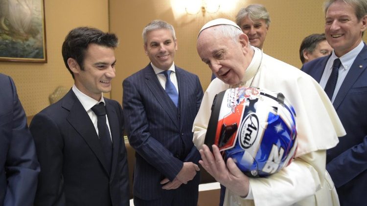 Pope Francis holds a MotoGP racer's helmet