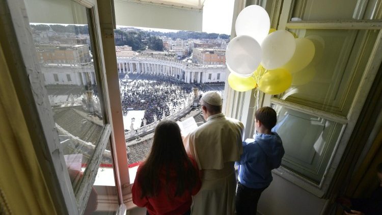 Pope Francis is accompanied at the Angelus by two children holding balloons