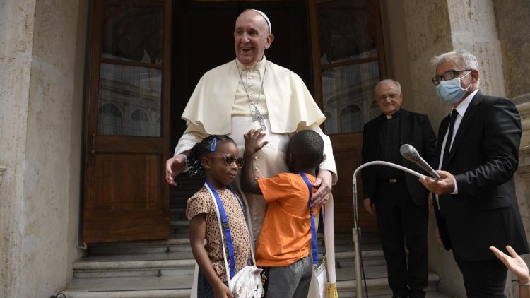 Der Papst und die Gruppe von Kindern zusammen mit der Flüchtlingspuppe