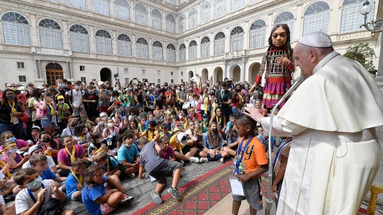 Der Papst und die Gruppe von Kindern zusammen mit der Flüchtlingspuppe