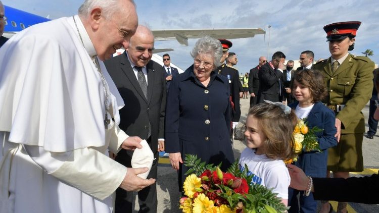 Ein Kind überreicht dem Papst zur Ankunft Blumen