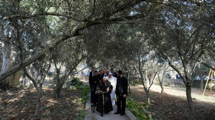 Pope Francis walking through the garden entrance to the migrant centre