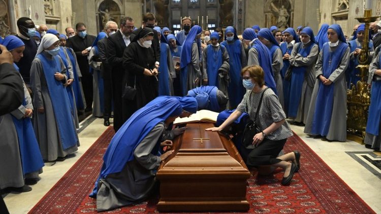 Des laïcs et des religieuses se recueillent sur le cercueil du cardinal.